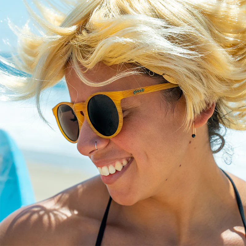 Person with short blonde hair wearing Gold Goodr sunglasses