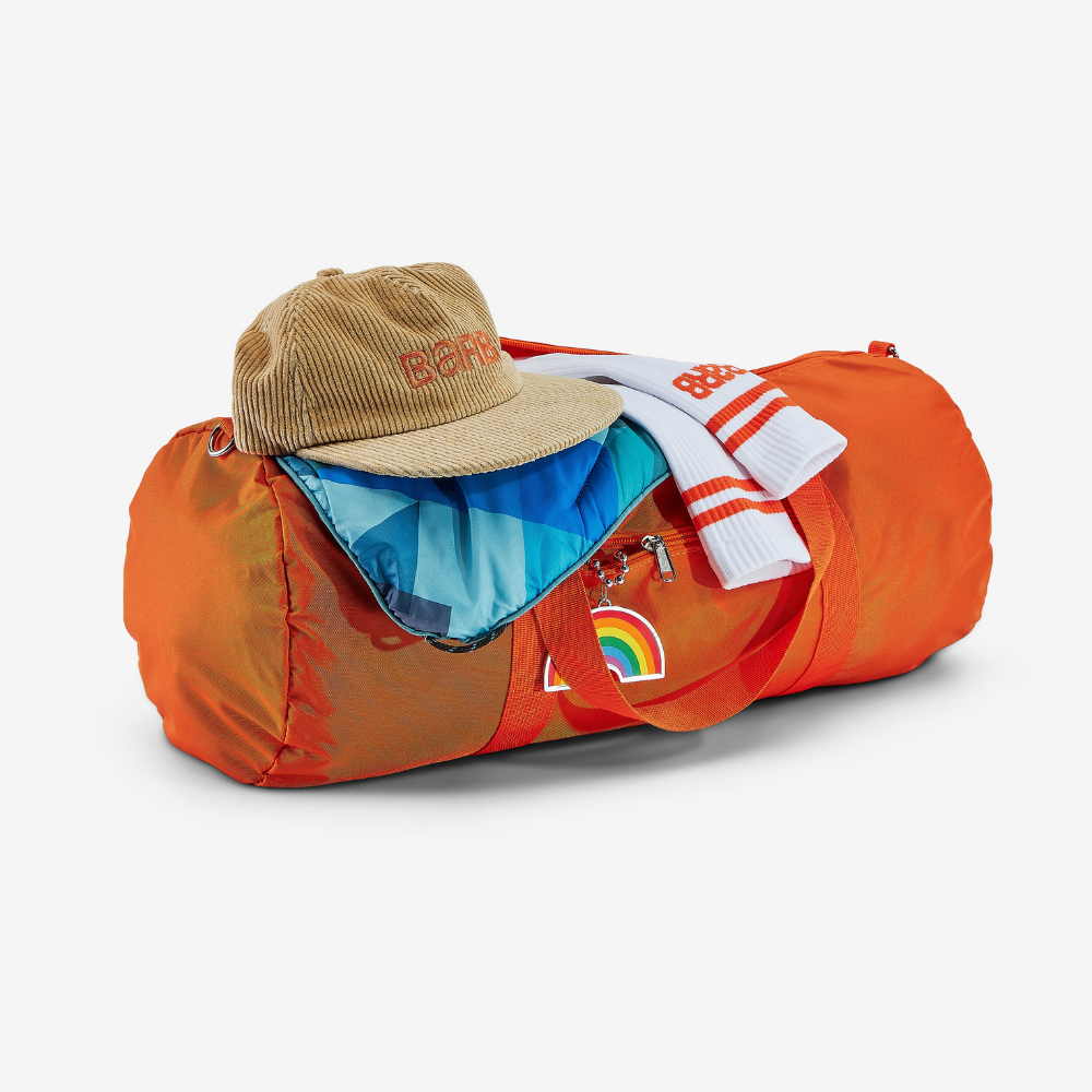 Orange un-branded duffel bag with corduroy Barb hat and striped socks laying across the top